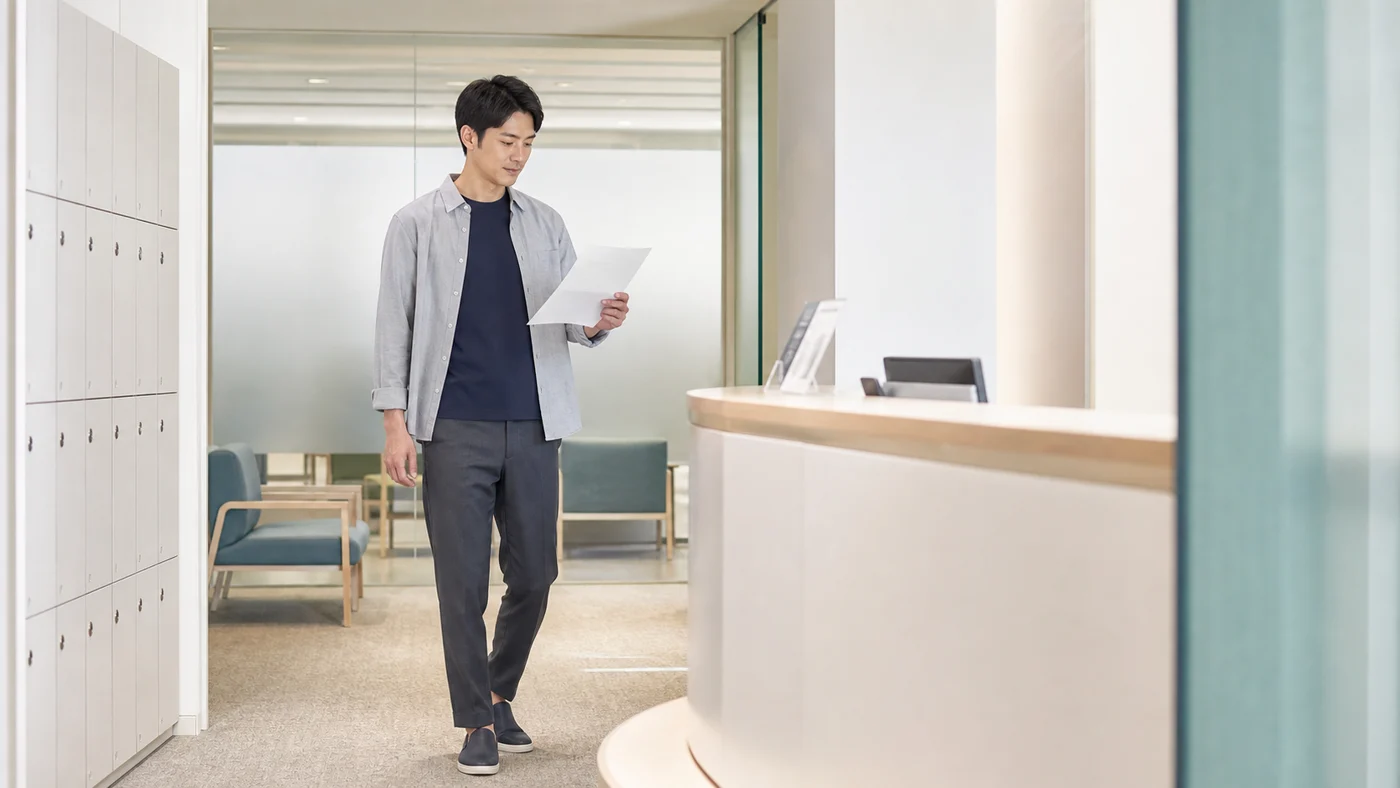 会社の健康診断会場で受診案内を確認する日本人会社員の検査しやすい服装