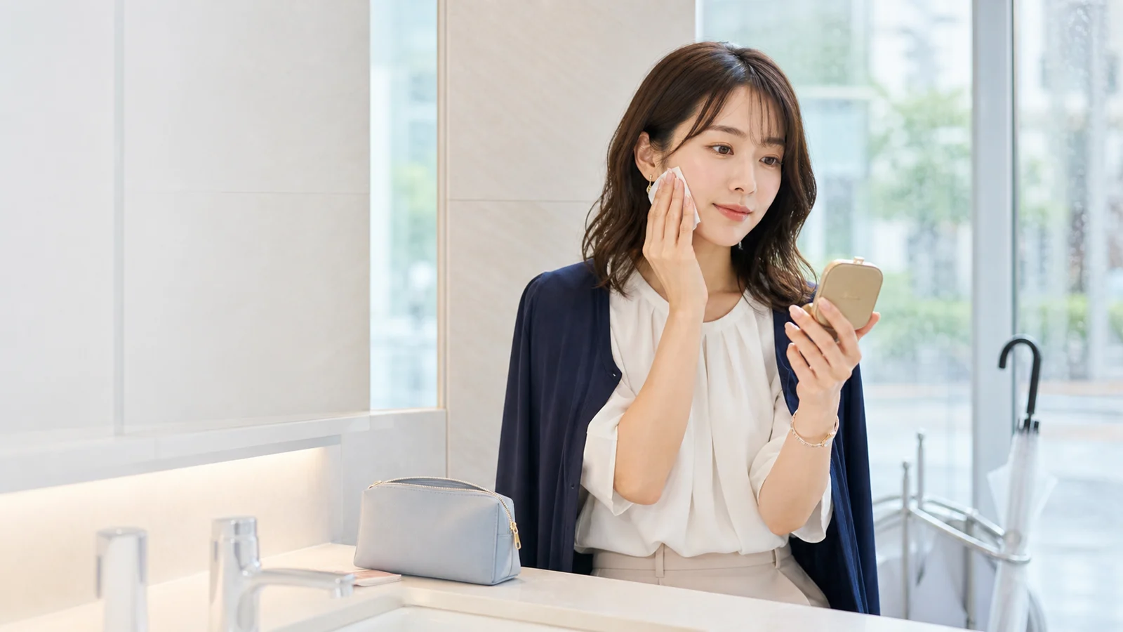 梅雨前の湿気で通勤メイクを会社前に直すオフィスカジュアル女性の画像