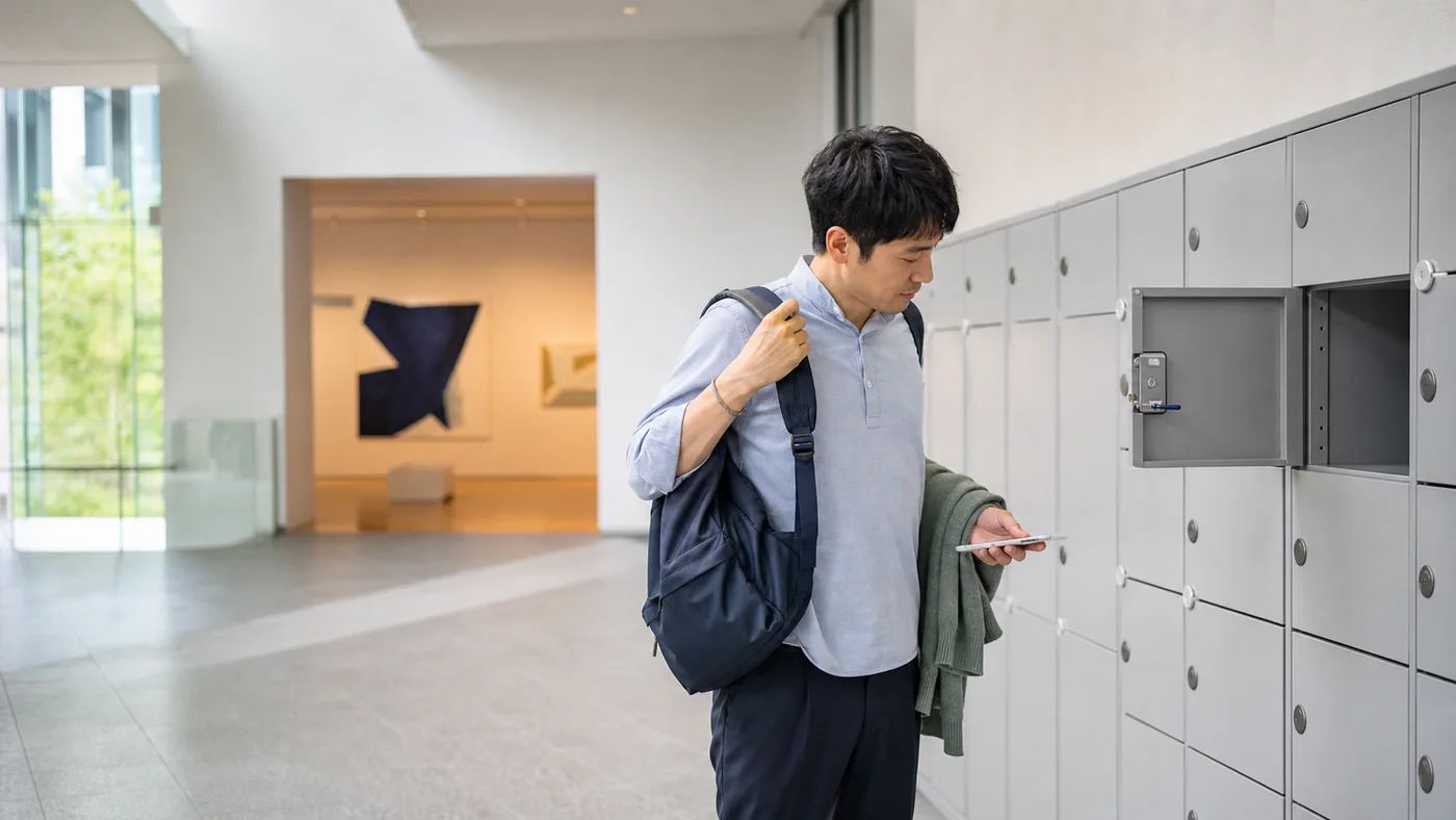 美術館の展示室へ入る前にコインロッカーでリュックを下ろす日本人来館者