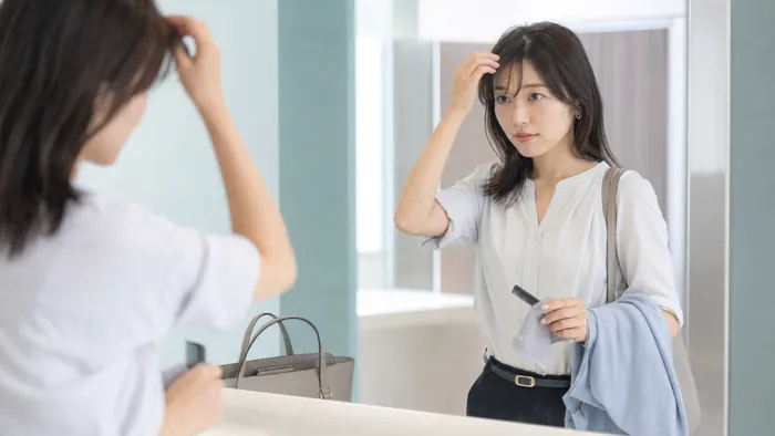 夏の通勤後に会社前で前髪と顔まわりの髪を整えるオフィス女性